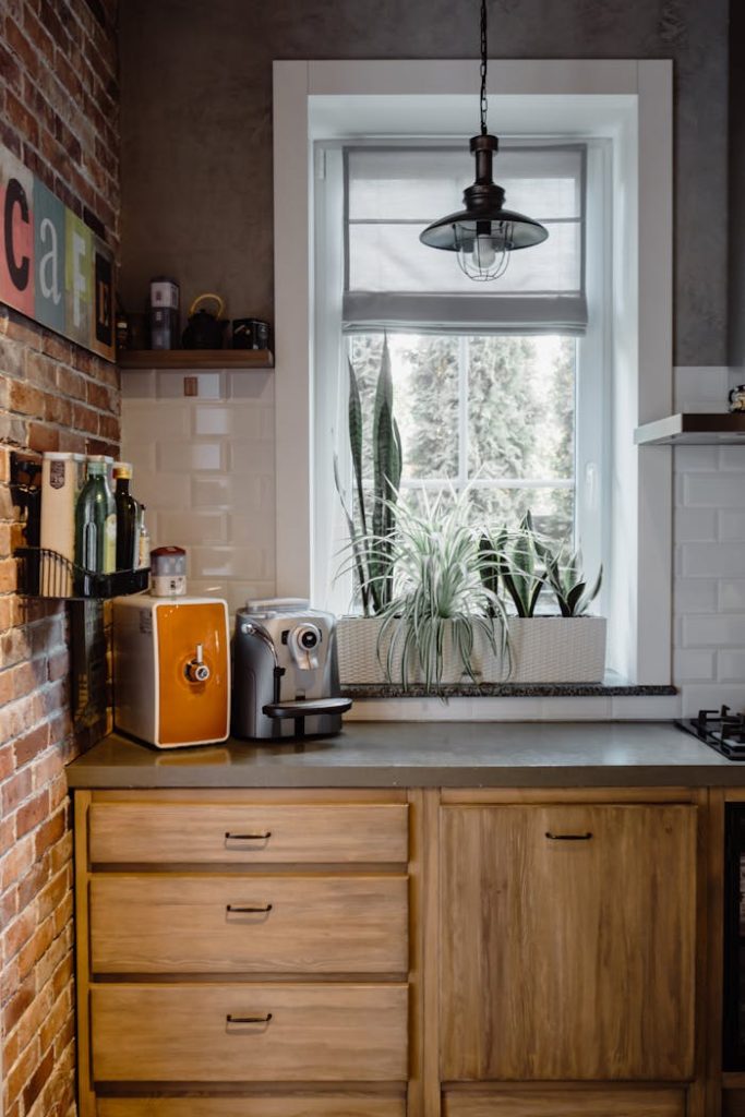 A bright kitchen space with rustic elements, featuring a coffee maker, plants, and brick accents.